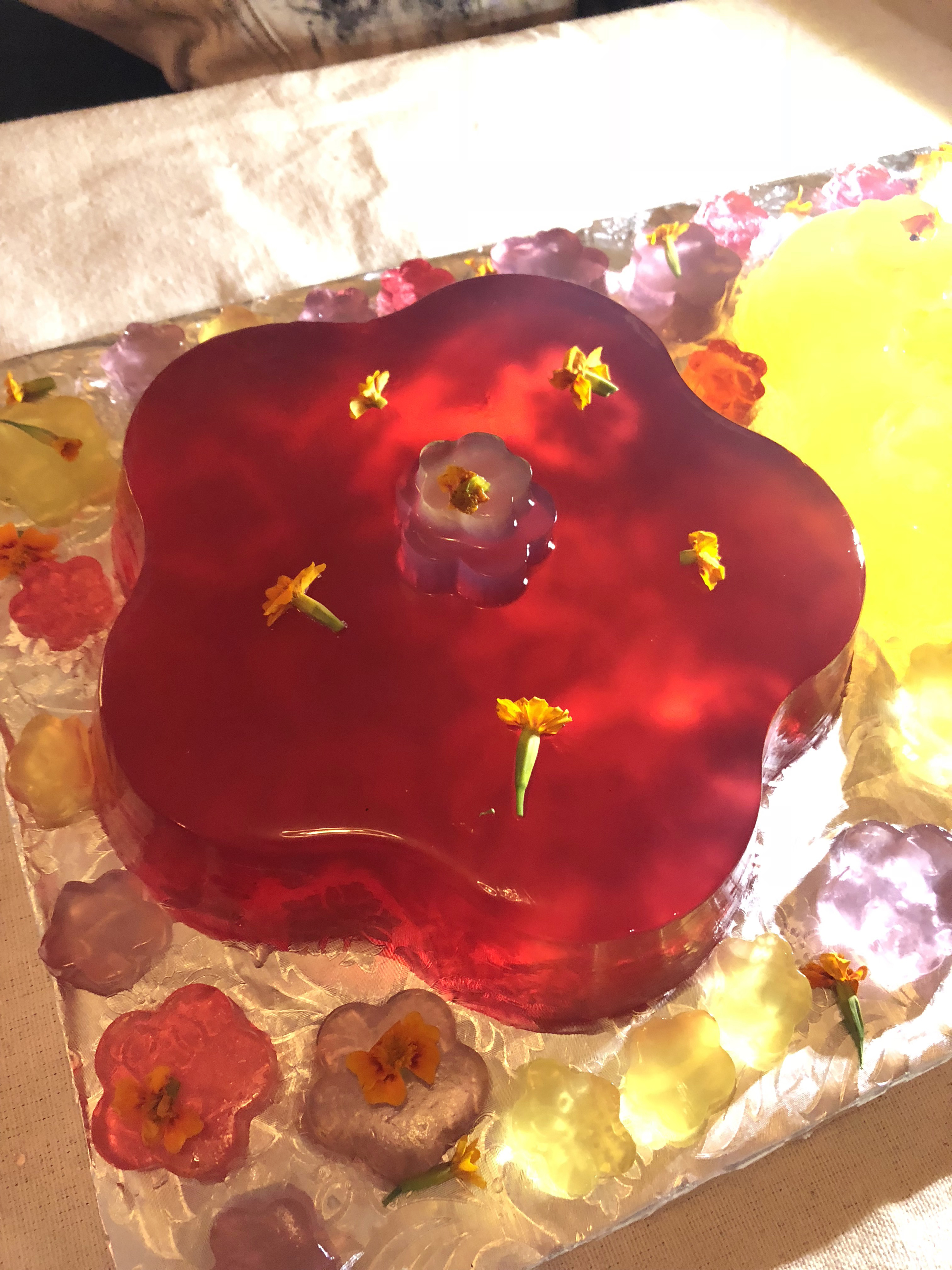 Detail of a brightly colored red jello cake in the shape of a flower on an alliuminium tray